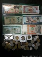 Full lot showing various international banknotes and coins spread out, including Kyrgyzstan 20 Som, Laos 2000 Kip, Peru 50 Soles among others, and multiple coins in various sizes.