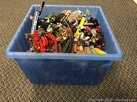 Blue plastic bin filled with assorted LEGO parts from side view