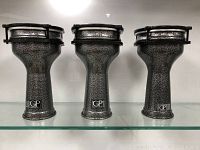 Front view of three matching Granite Percussion darbuka drums with unique speckled granite-style metal shells on shelf.