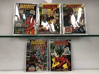 Front view of five Daredevil comics in plastic sleeves arranged on a glass surface.