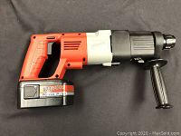 Side view of the Milwaukee cordless hammer drill showing red, black, and gray body with 18V Power-Plus battery attached, and side handle for grip.