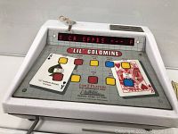 Front angled view of the 'Lil Goldmine' gambling machine showing the playing surface with large card graphics, multiple color-coded buttons, and digital LED window. Key attached.