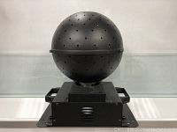 Front view of black spherical star projector with multiple small holes mounted on a metal base with handles.