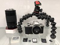 Overview of Olympus camera body, Canon lens, Joby GorillaPod and memory cards with adapters on shelf