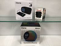 Front view of iHome Bluetooth Dual Alarm Clock Radio with USB Charging box and Melody sport speaker box displayed on shelf.