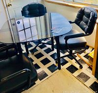 Dinette set showing smoked glass round edge table with four black cushioned rolling chairs in room