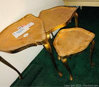Three gold triangular side tables nested together showing shape and sizes
