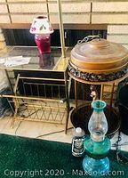 Photo showing pink glass candle lamp with floral shade on a gold-toned stand, green glass oil lamp in front, and the decorative hanging bronze lamp with figurine on the side.