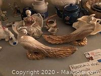 Two large peacock figurines and various small porcelain pieces on table