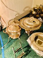 Two silver plated lidded dishes on ornate stands and a small burner stand