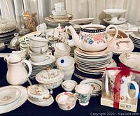 Overview of assorted china and tea set items including teapots, plates, cups, and serving dishes in various floral and gold designs.