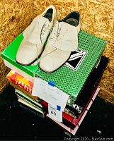 Pair of white women's leather dress shoes with fringe on laces, displayed on shoe boxes.