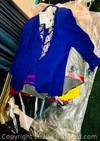 Royal blue long-sleeve jacket with silver sequin embroidery, laid over assorted garments in plastic wrapping
