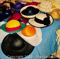 Various women's hats arranged on a blue cloth background showing styles, colors, and materials.