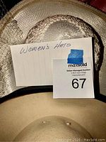 Photo of three women's hats shown stacked: cream wide-brim straw hat, textured tan woven straw hat, beige fabric hat with pearl decoration.