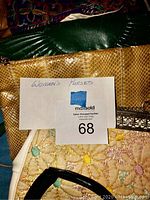 Photo showing four women's purses: dark green purse with braided trim, yellow snakeskin purse, cream purse with floral embroidery, and black purse with silver metal decoration.