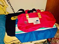 Three bags stacked on a chair, showing different colors and styles.