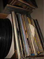 Cardboard box of various 12" LP album covers and stacked vinyl discs