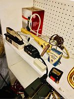 Shelf with power strips, stapler, hammer, clamps, cords, and anti-dust tool.