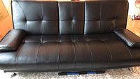 Front view of black vinyl tufted futon in sofa position