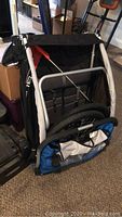 Folded stroller showing aluminum frame, black seat fabric, blue trim