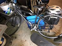 Side view showing gray Gary Fisher Wingra bicycle leaning against storage items with helmet on rear rack and skateboard under front wheel