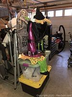 Lot containing Halloween decorations including a posable skeleton, large tombstone with 'Stay Scary' text, and witch hat on a figure