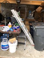 Overview of the 6-foot aluminum step ladder leaning against a table and near bins, showing the item for sale in typical garage or storage area.