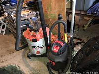 Side by side view of the Ridgid 16 gallon wet dry vacuum and the black and red 6 gallon Shop-Vac, showing hoses and attachments.