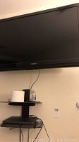Front view of the Insignia 39-inch wall mounted TV above the component shelf with items on shelf