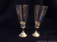 Pair of Cartier sterling silver hurricane lamps with etched glass shades shown side by side. One shade is broken.