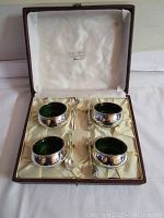 Set of 4 silver salt cellars with emerald green glass bowls and four silver spoons in a presentation box.
