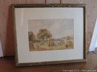 Framed watercolor painting leaning against a wall, showing full frame and matting.