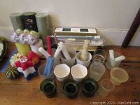 Photo of assorted candles including pillars, themed and shaped candles and votive holders arranged on a wooden floor.