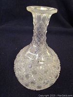 Full side view of clear cut glass decanter with intricate hobnail and diamond cut patterning on sphere-shaped body and neck