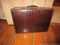 Front view of vintage leather suitcase with crocodile pattern and handle on top.