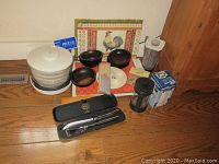 Full lot overview showing multiple kitchen items including carving set, salad bowls, salad spinner, grinder, placemats, and other accessories.
