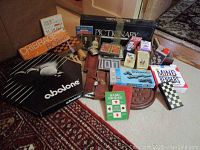 Photo showing multiple boxed and unboxed board and card games including Abalone, Pictionary, Cribbage board, Dominoes, playing cards, and several other game pieces and accessories.
