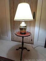 Brass table lamp on pie-shaped leather top table, lit lamp showing appearance and height