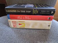 Stack of three hardcover books: 'Lessons from the Top', 'Ride the Wave', and 'Muzik Manifesto'