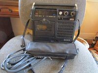 Sony portable cassette player shown from side view with charger and strap visible.