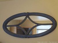Blue painted oval wall mirror with curved wooden muntins creating decorative sections within the frame, showing some wear.