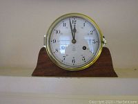 Front view of the Royal Mariner mantel clock showing clock face with hour, minute and second hands, white dial with black Arabic numerals and a brass bezel mounted on a wooden base.