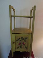 Small yellow painted wood storage table with cabinet door featuring two birds and leaves painted on the front panel