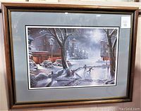 Framed winter scene print showing village and skaters in moonlight.