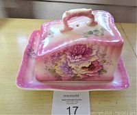 Front and side view showing pink floral cheese dish with cover and handle on a wooden surface
