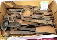 Photo showing 17 antique tools including adjustable spanners and wood handled tools in a cardboard box