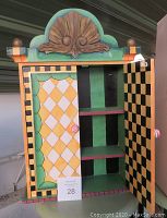 Front view of colorful wooden shelving unit with open door showing three shelves and decorative painted designs.