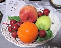Ceramic fruit bowl showing colorful ceramic fruits including apple, orange, pear, cherries, and decorative leaves in white ceramic basket
