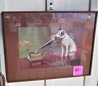 Framed art print hanging on wall showing dog listening to phonograph horn with Victor branding visible. Piece includes matting and glass covered frame with some reflections and minor wear visible.